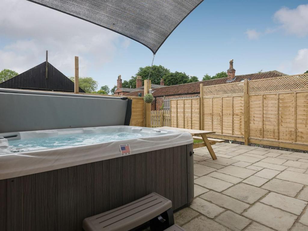 a hot tub on a patio with an umbrella at Haven View - Ukc2301 in Wainfleet All Saints