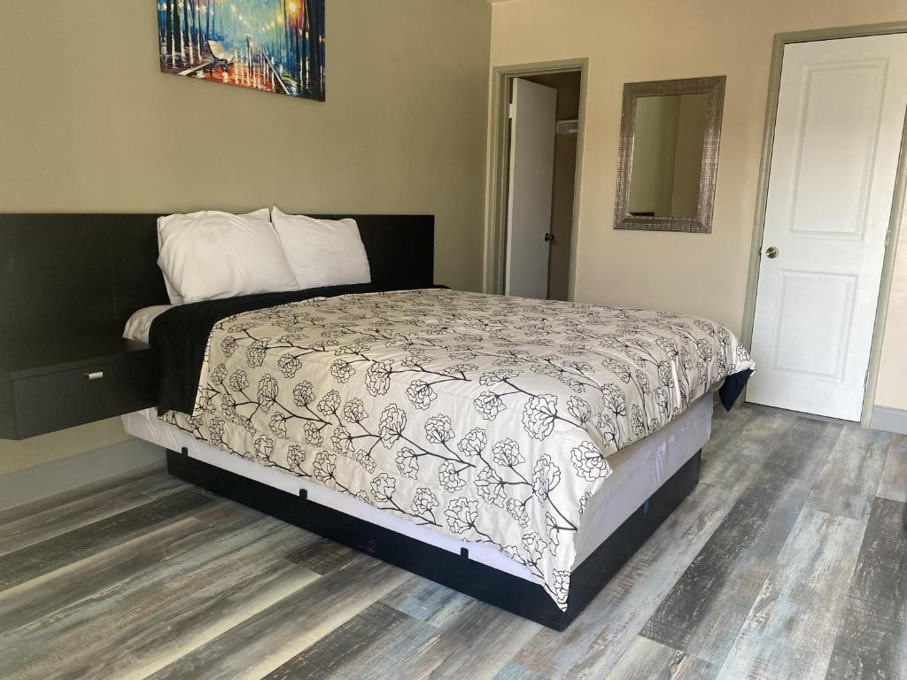 a bedroom with a bed with a black and white comforter at City Center Motel in Oxnard