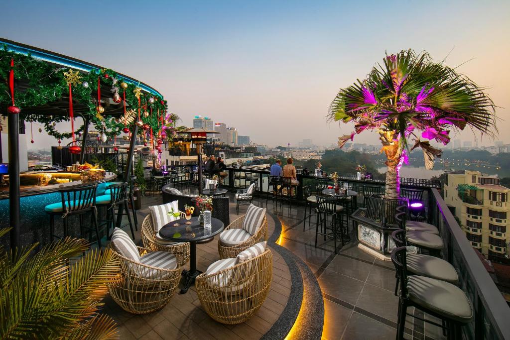 a restaurant with tables and chairs on a balcony at Lucien Hanoi Lakeside Hotel & Rooftop in Hanoi