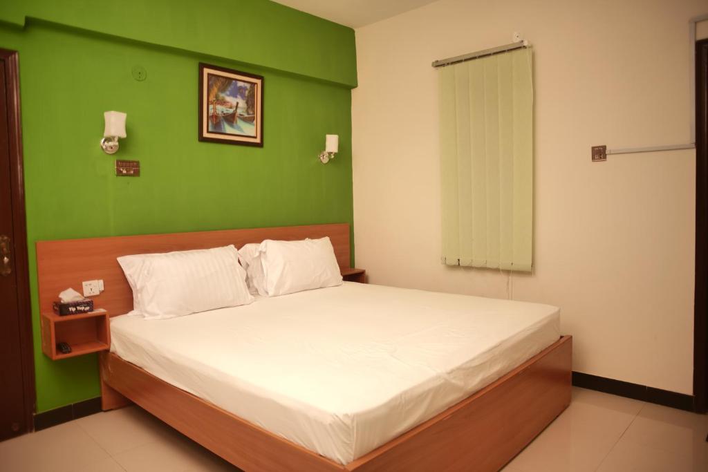 1 dormitorio con 1 cama con pared verde en Diamond Apart's Dha Karachi en Karachi