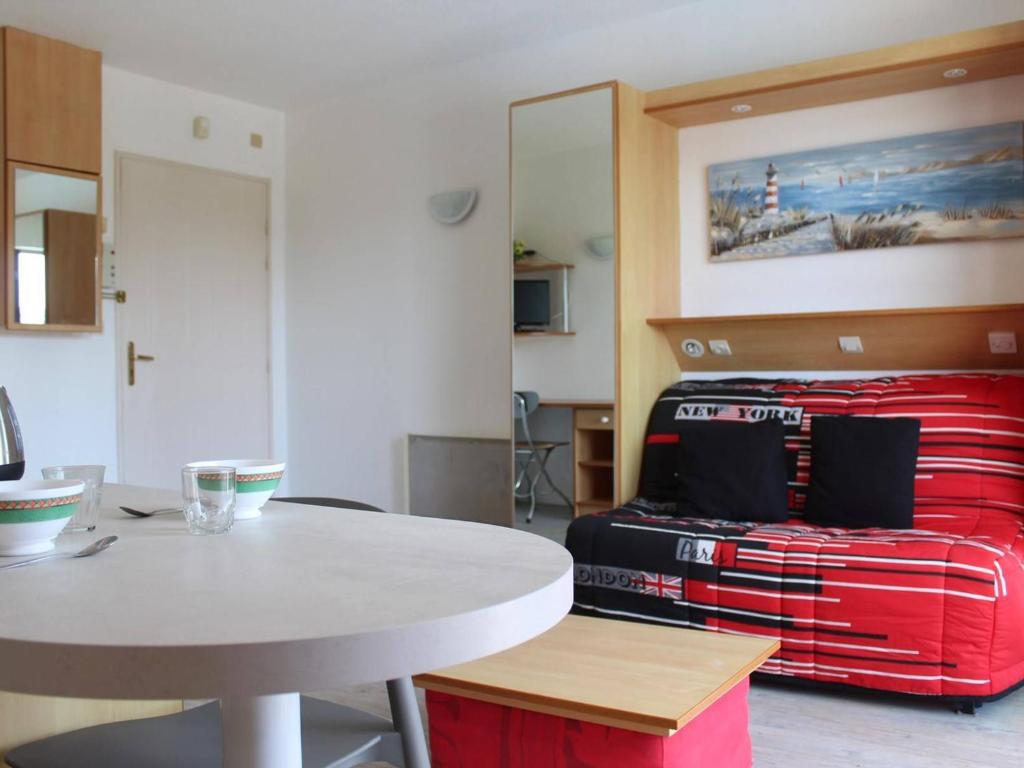 ラ・ロシェルにあるAppartement La Rochelle, 1 pièce, 2 personnes - FR-1-246-137のテーブルと赤いスーツケース付きのベッドが備わる客室です。