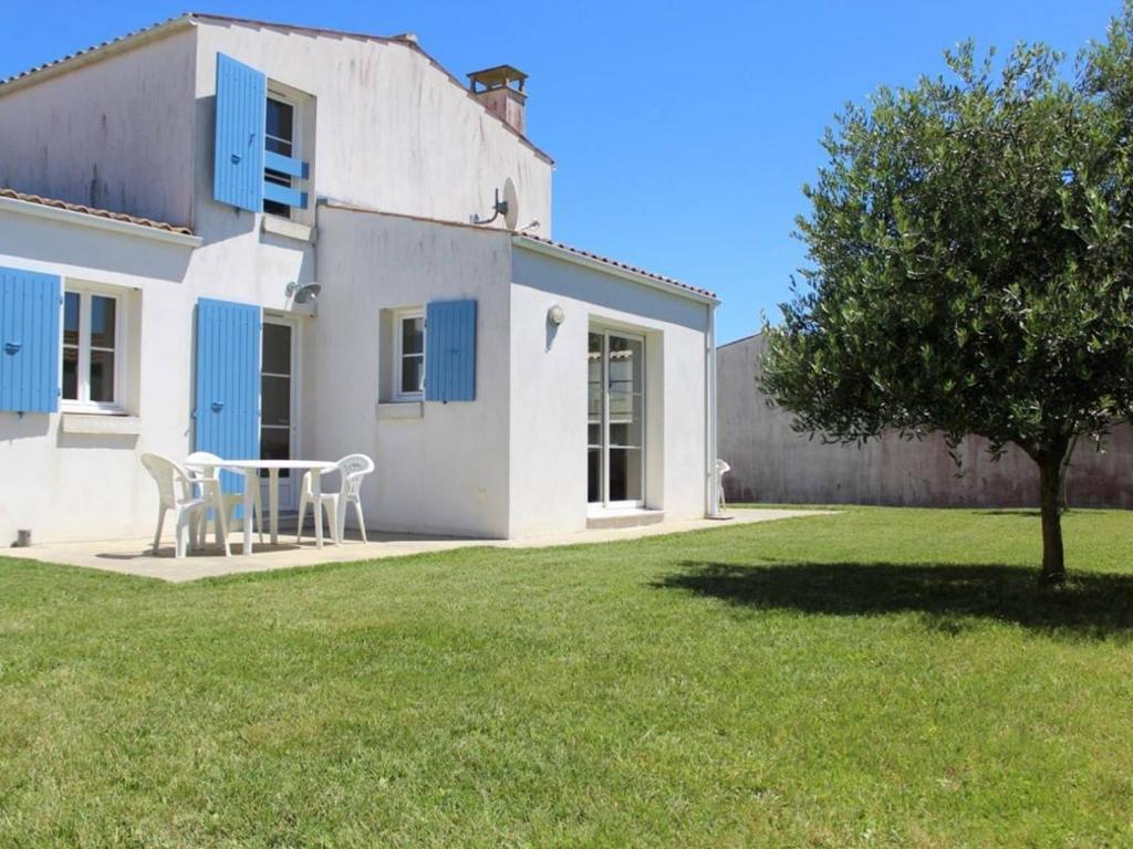 une maison avec une table et des chaises dans une cour dans l'établissement Maison avec Jardin, 6 Couchages, Proche Plages et Pistes Cyclables, Saint-Denis-d'Oléron - FR-1-246A-406, à La Michelière