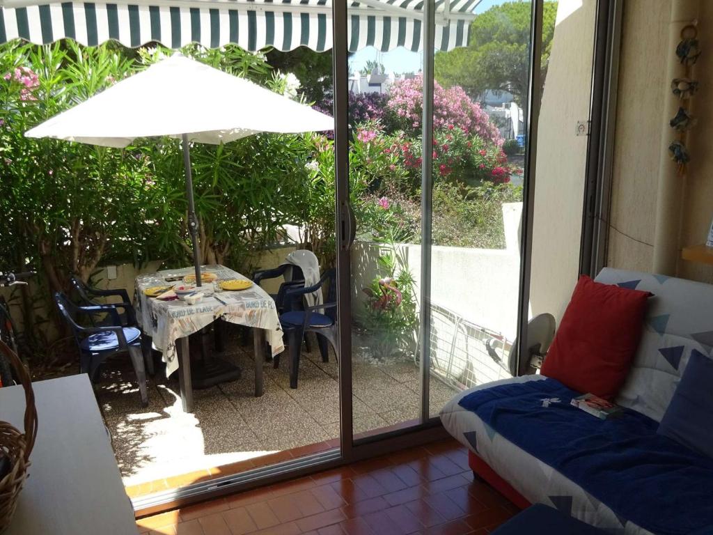 ein Wohnzimmer mit einem Tisch und einem Sonnenschirm in der Unterkunft Appartement Port Camargue, 1 pièce, 4 personnes - FR-1-250-196 in Le Grau-du-Roi