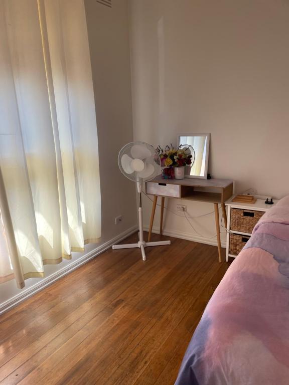 a bedroom with a desk and a fan and a bed at Private Room Near Melbourne Airport in Deer Park