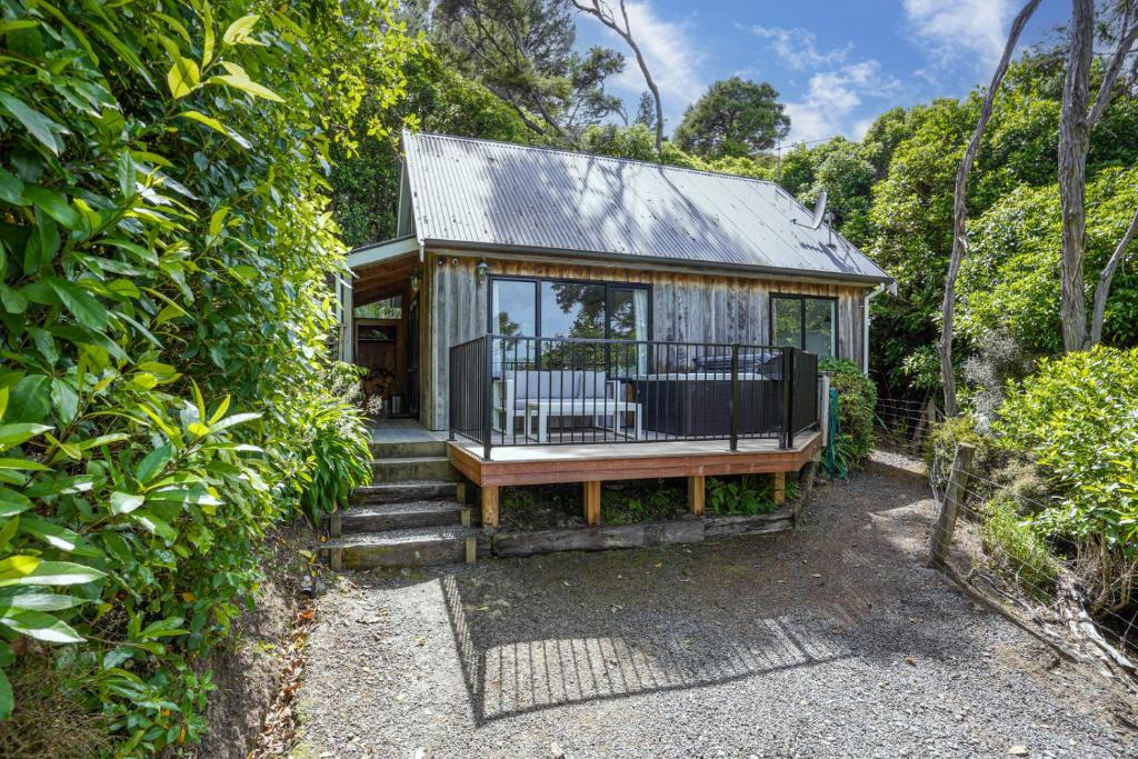 une petite maison avec des portes en verre et une véranda dans l'établissement Bushside Cottage - Akaroa Holiday Home, à Akaroa