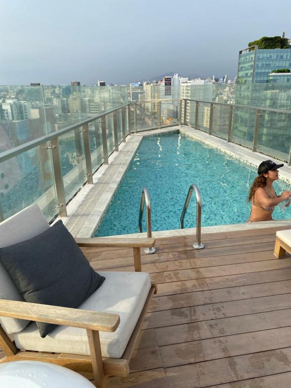a woman sitting next to a swimming pool on a building at Moderno departamento Miraflores 360 in Lima