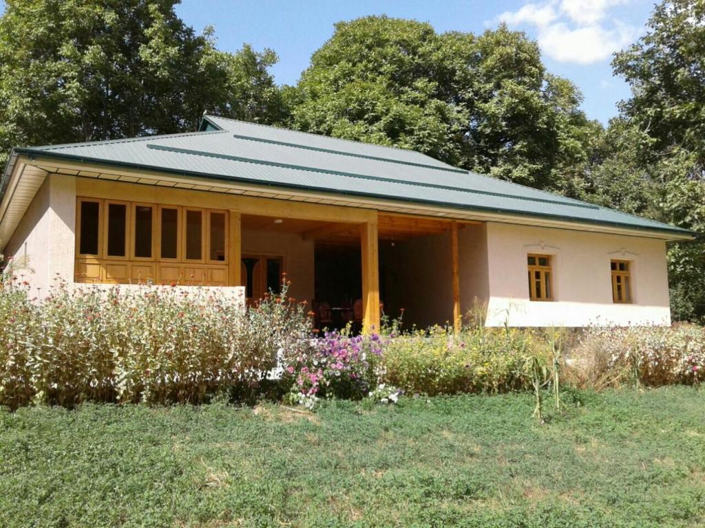 mały biały dom z zielonym dachem w obiekcie Hayat Guesthouse Nuratau Mountains w mieście Yukary-Ukhum