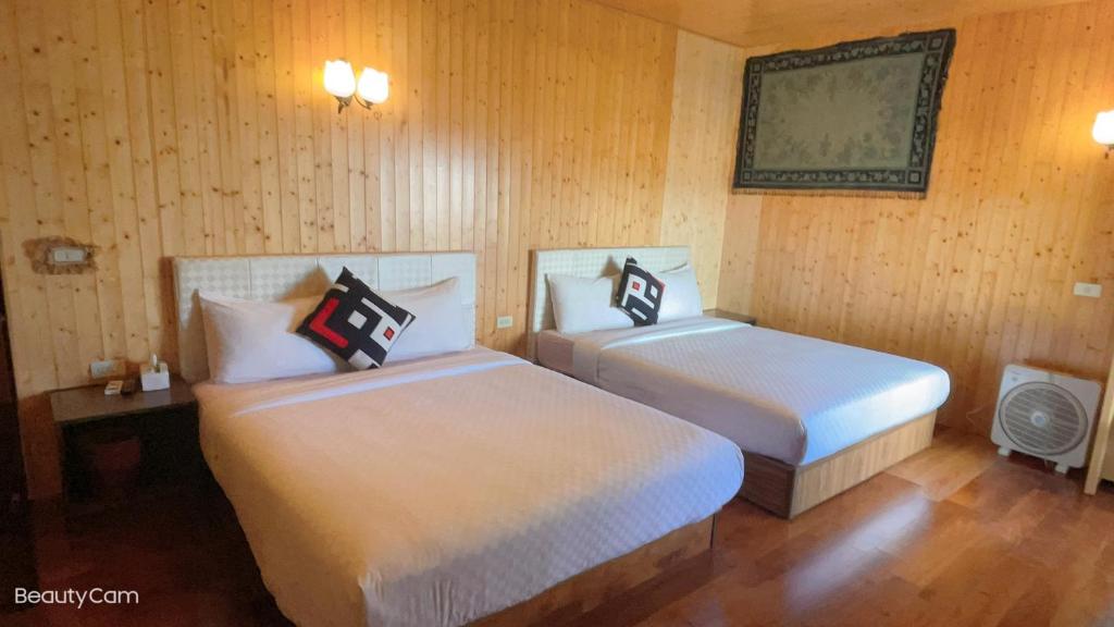 two beds sitting in a room with wooden walls at 寧靜的家14人Villa獨立設施包棟戲水池烤肉區麻將廚房私人停車場 in Hengchun South Gate