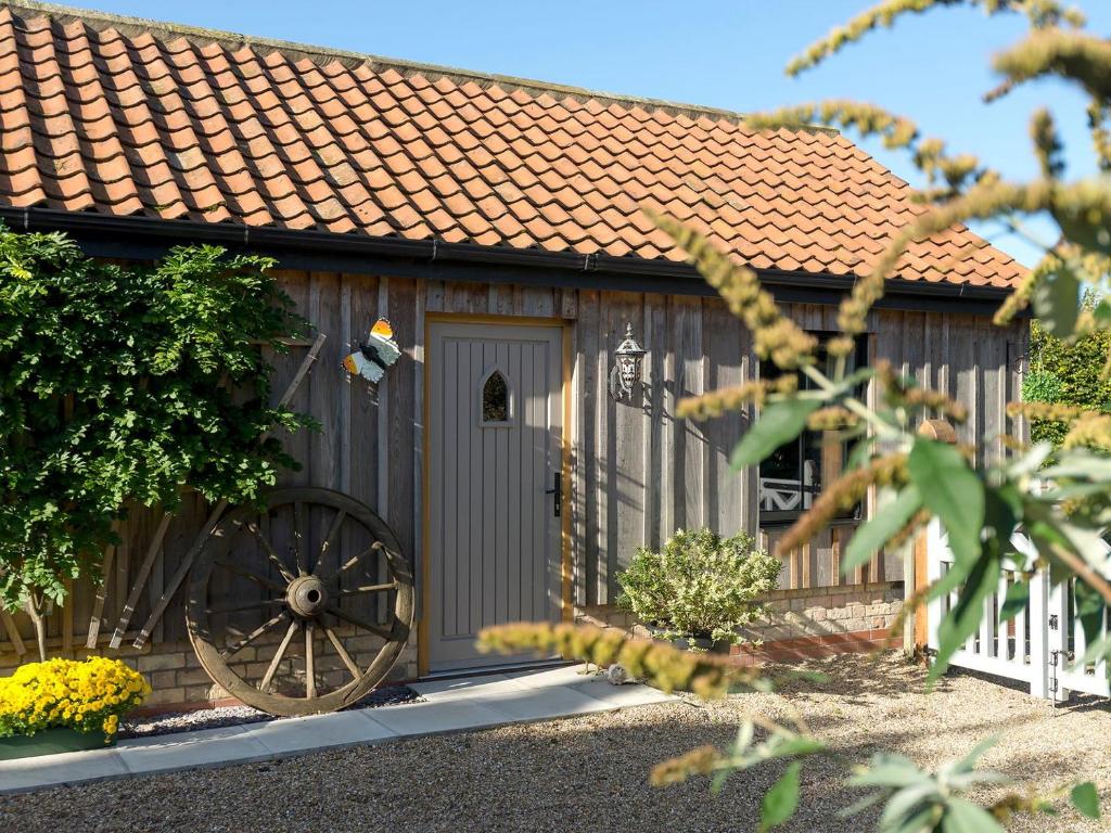 Benniworth的住宿－Homestead Cottage，院子中带轮子的木制谷仓