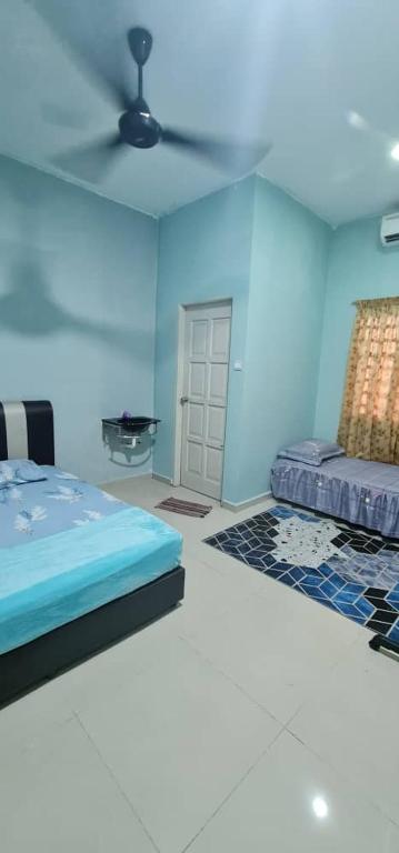 a blue room with a bed and a ceiling fan at AFIA CHUKAI HOMESTaY in Cukai