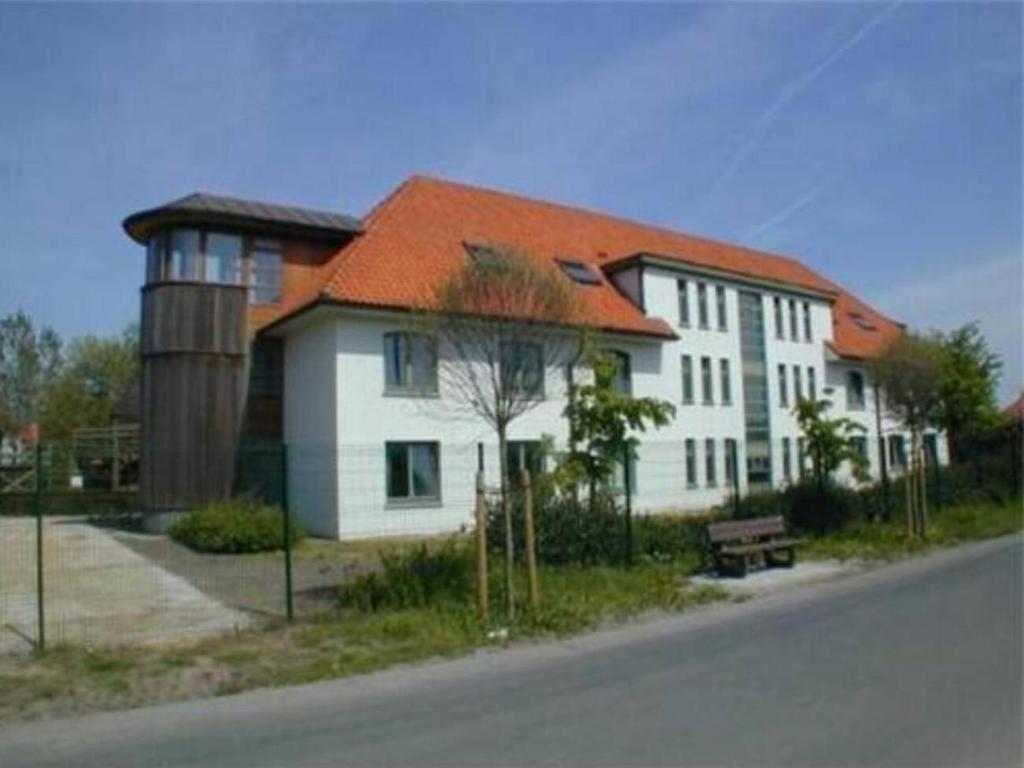 una casa blanca con techo naranja junto a una calle en APPARTEMENT WESTENDE (DRIEMASTER), en Middelkerke
