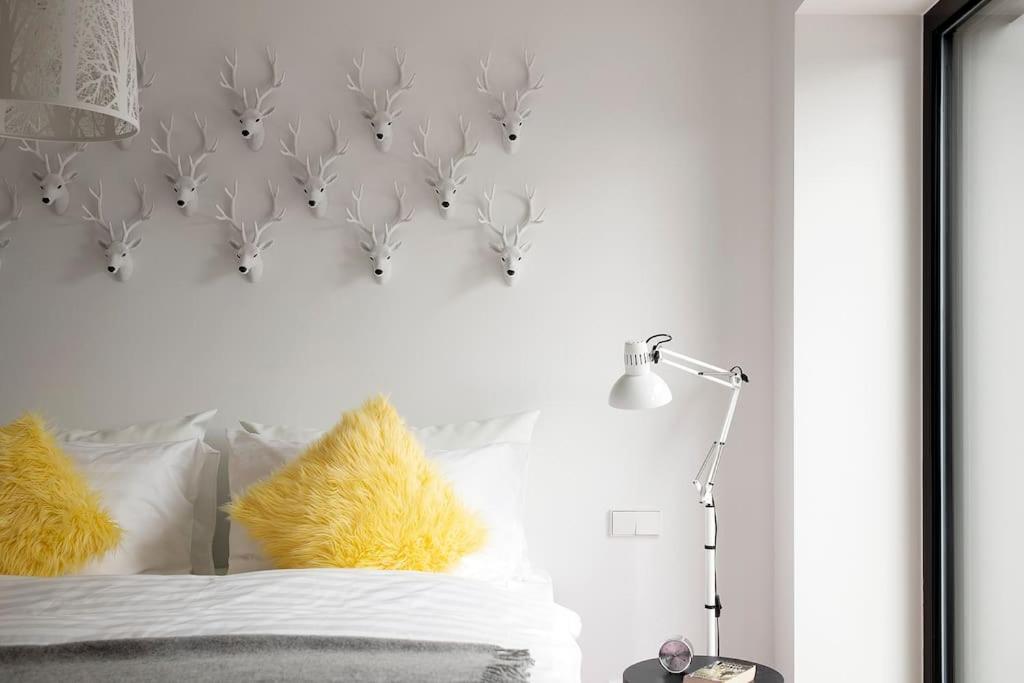 W Apartments Kalaranna III في تالين: غرفة نوم بجدار أبيض مع سرير مع وسائد صفراء