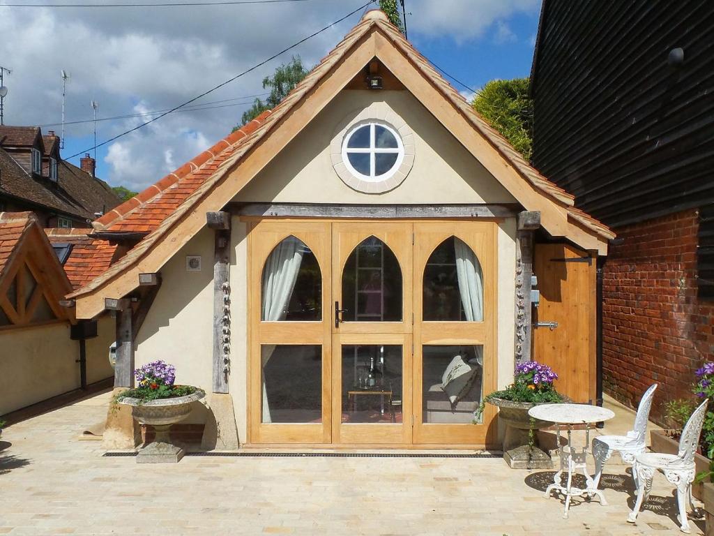 a small house with a large window and a patio at The Cart Shed in Ibstone