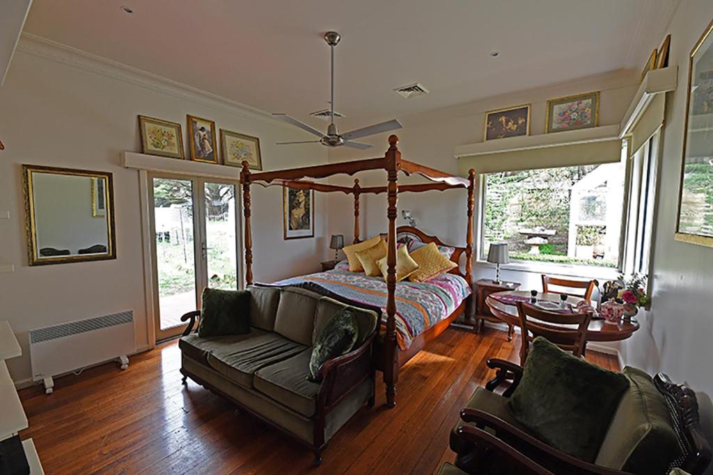 1 dormitorio con cama con dosel y sofá en Galahad's Animal Sanctuary B&B en Gisborne