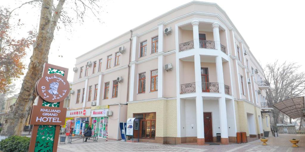 un edificio blanco con un cartel delante en Khujand Grand Hotel, en Khujand