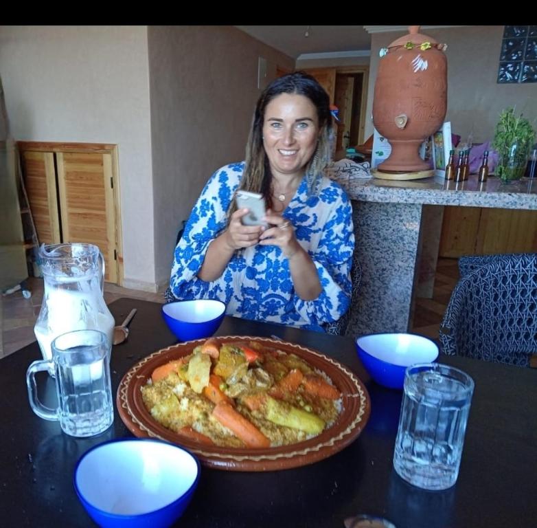 a woman sitting at a table with a plate of food at Dar diafa samira in Mirleft