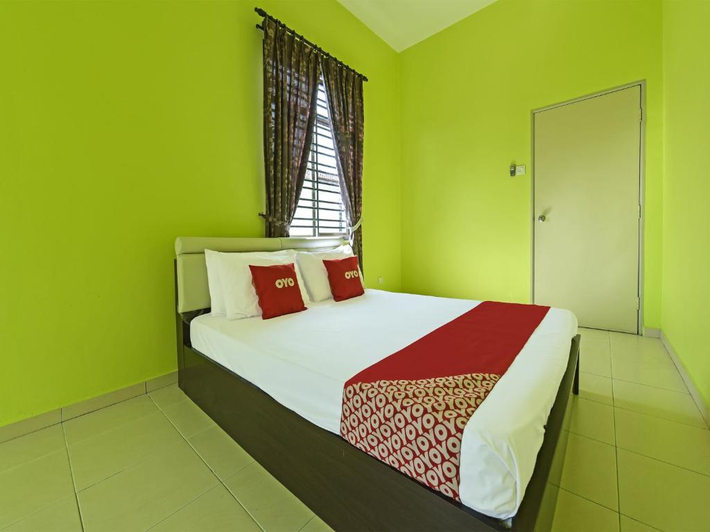 Un dormitorio con una cama con paredes verdes y una ventana en OYO Home 90532 Casa Azlinda Muslim Homestay Ii en Johor Bahru