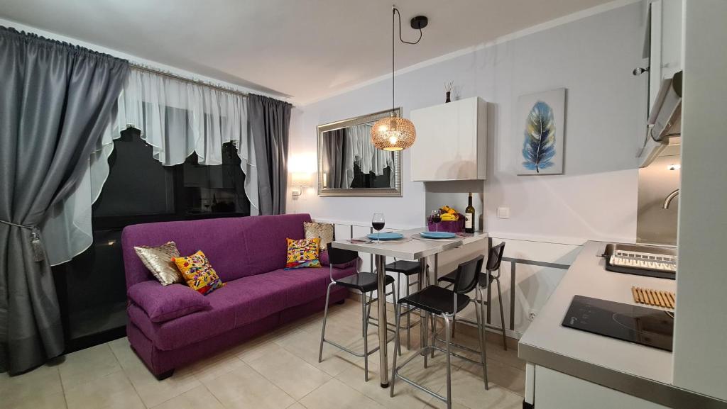 コスタ・カルマにあるHoliday house Fuerteventuraの紫色のソファとテーブル付きのリビングルーム