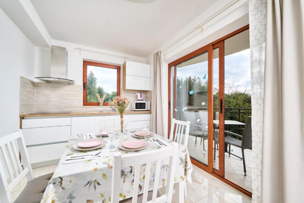 een keuken en eetkamer met een witte tafel en stoelen bij Elia Apartments in Savudrija