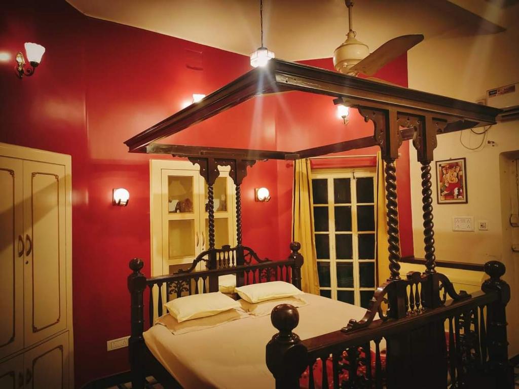 加爾各答的住宿－OH Kolkata - Sutanuti Homestay，一间红色客房内的卧室,配有一张天蓬床