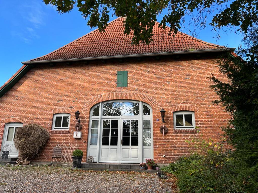 una casa de ladrillo rojo con puerta blanca en Ferienhof Sandmann en Wangels