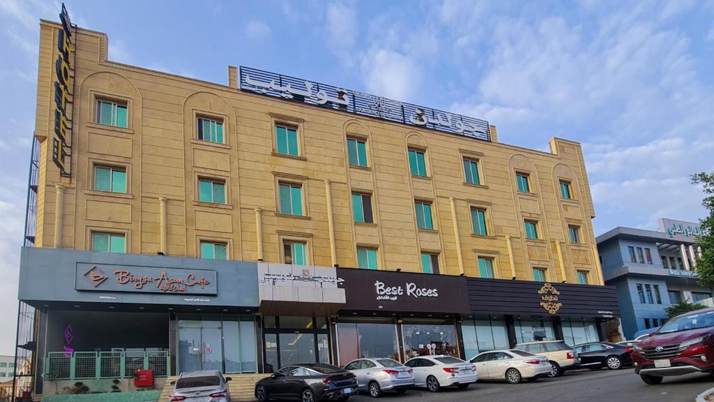 فندق جولدن توليب أبها - GOLDEN TULIP ABHA HOTEl في أبها: مبنى أصفر كبير فيه سيارات متوقفة أمامه