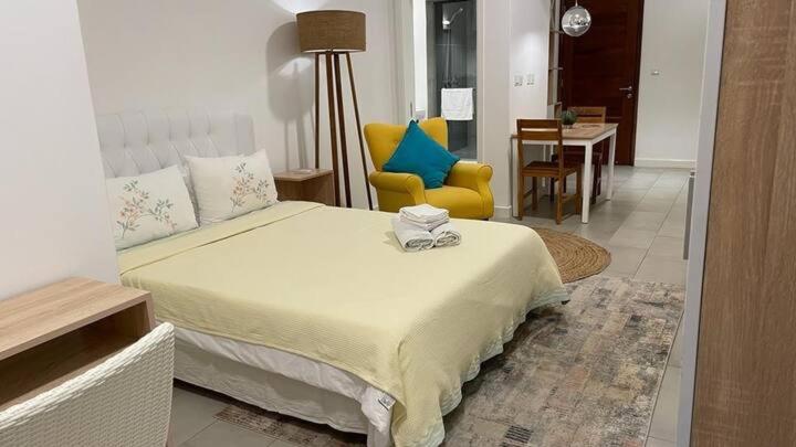 um quarto com uma cama e uma cadeira amarela em Studio 104 Ebene Square Urban Living Apartments em Ebene