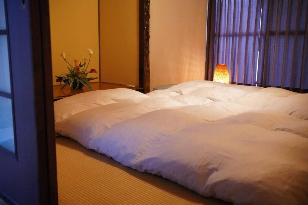 uma grande cama branca num quarto com uma janela em 吉田邸　古民家の落ち着いたお家 
