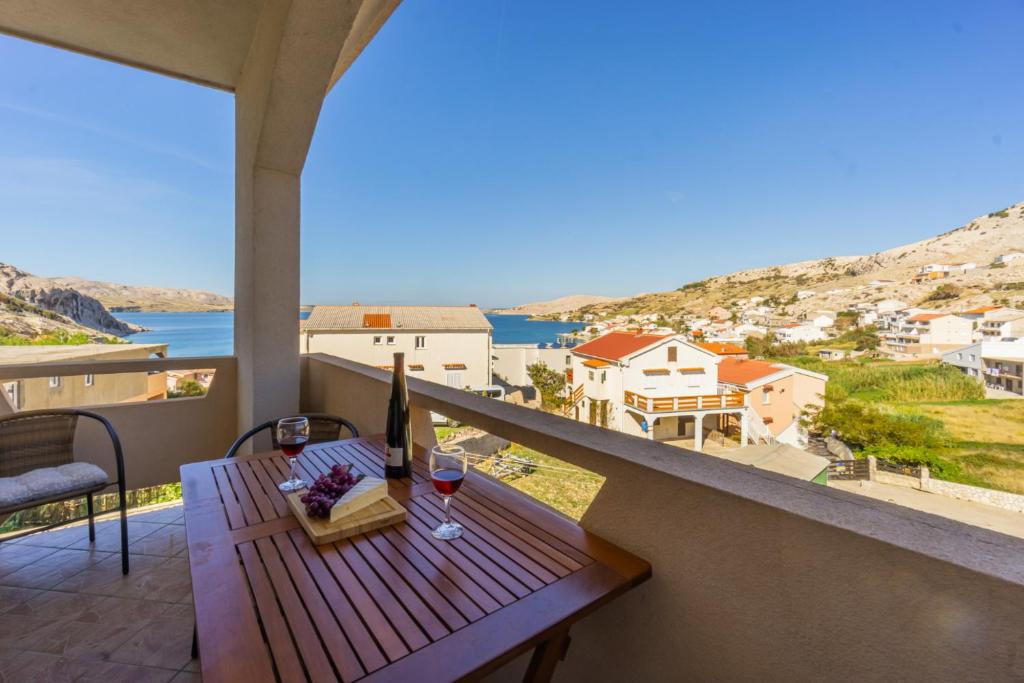 uma varanda com uma mesa de madeira e copos de vinho em Apartment and Room Bacic em Metajna