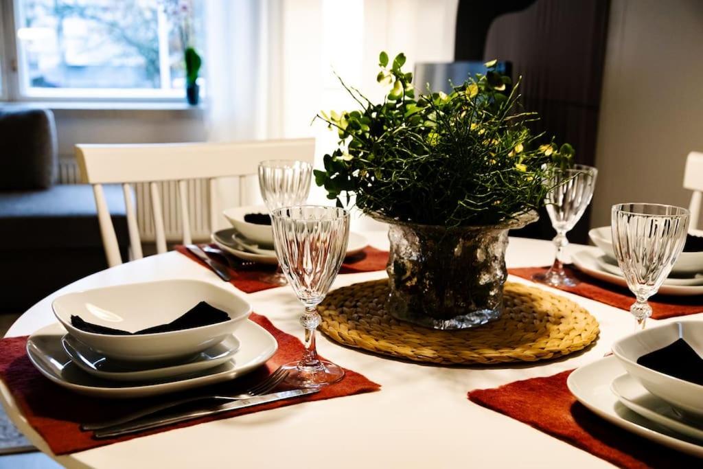 a table with plates and glasses and a vase with flowers at Mukava saunallinen kaksio omalla sisäänkäynnillä ja ilmaisella autopaikalla in Kuopio