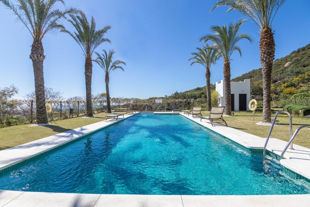 una piscina con palmeras en el fondo en 2156-Luxury apt in Cortesin golf with pool view, en Casares
