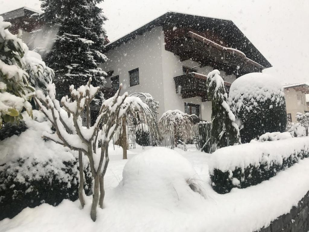 un patio cubierto de nieve frente a una casa en Appartements Gästehaus Schrott, en Oetz
