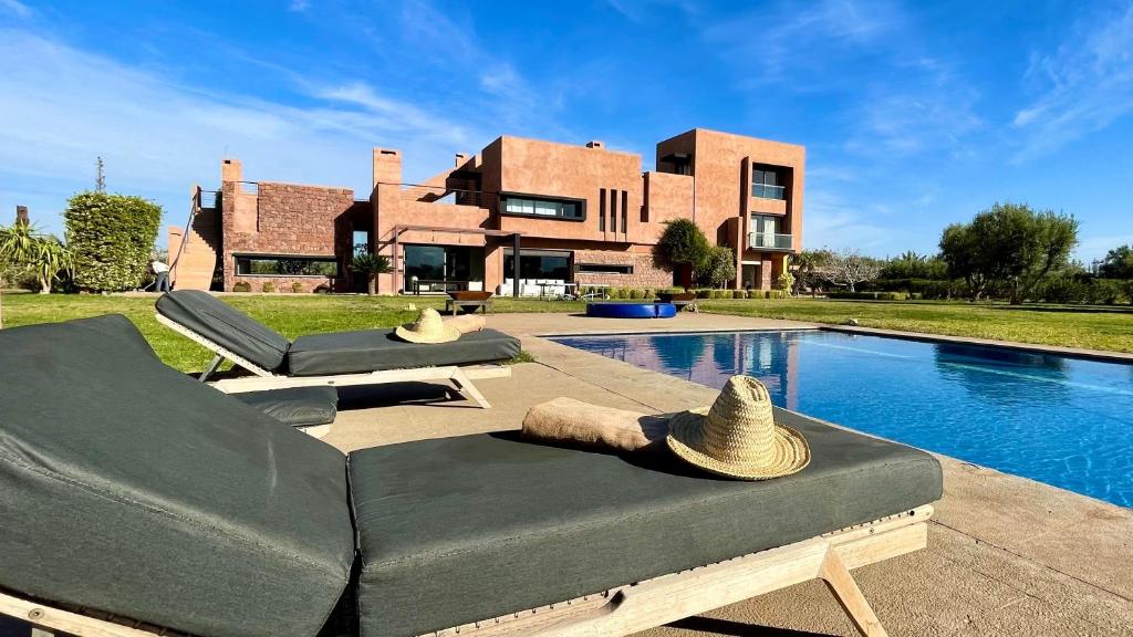 ein Haus mit zwei Sofas und einem Pool in der Unterkunft Villa Les Palmiers De L'atlas in Marrakesch