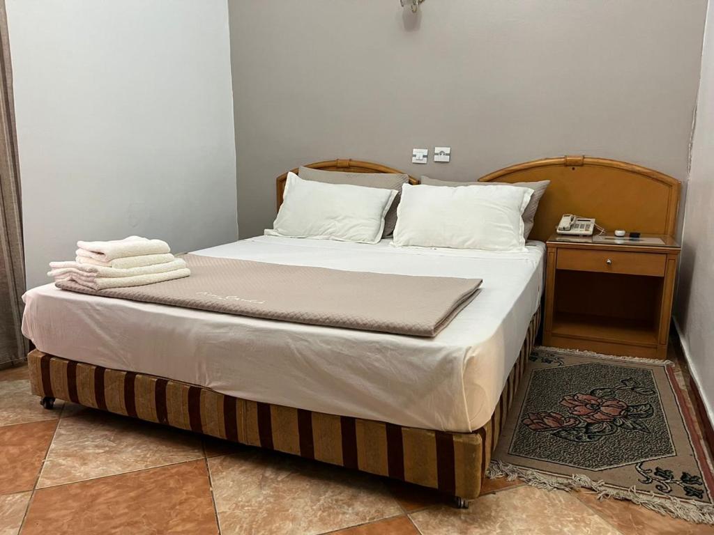 1 cama con sábanas blancas y almohadas en una habitación en Le cheval blanc en Orán