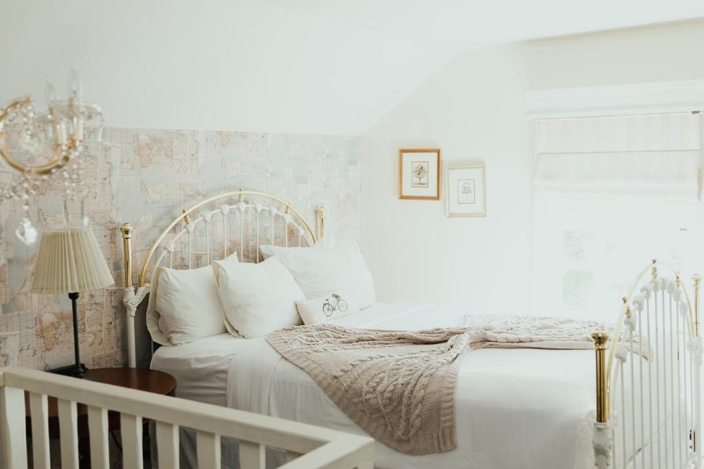 a white bedroom with a bed and a crib at La Villa de Adelina in Ensenada