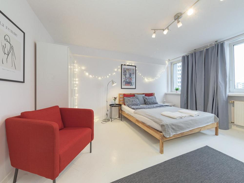 a bedroom with a bed and a red chair at Sliska apartment Warsaw in Warsaw