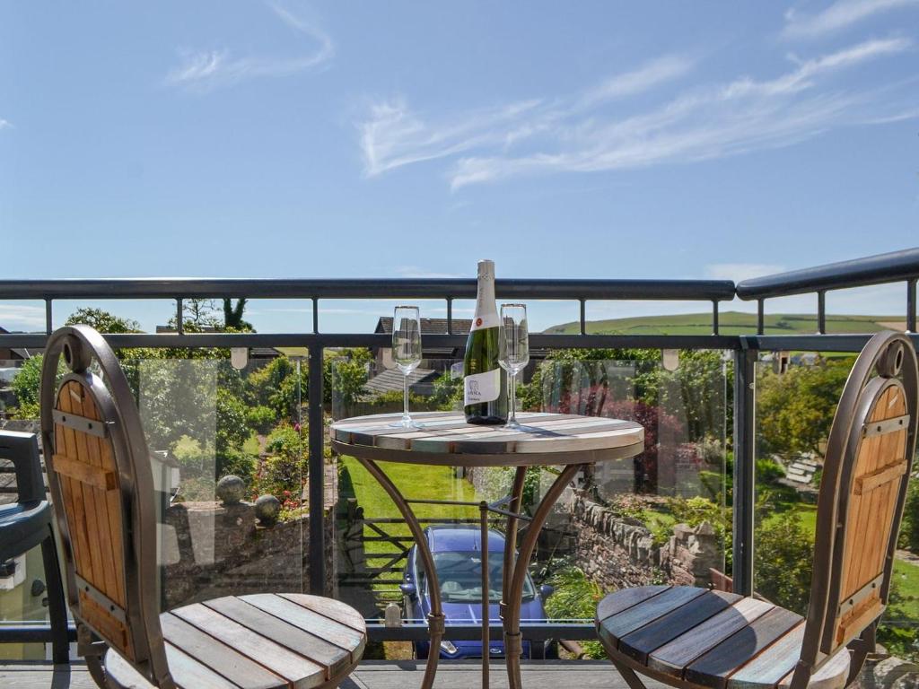 a table with two chairs and a glass of wine on a balcony at Hurst House in St Bees