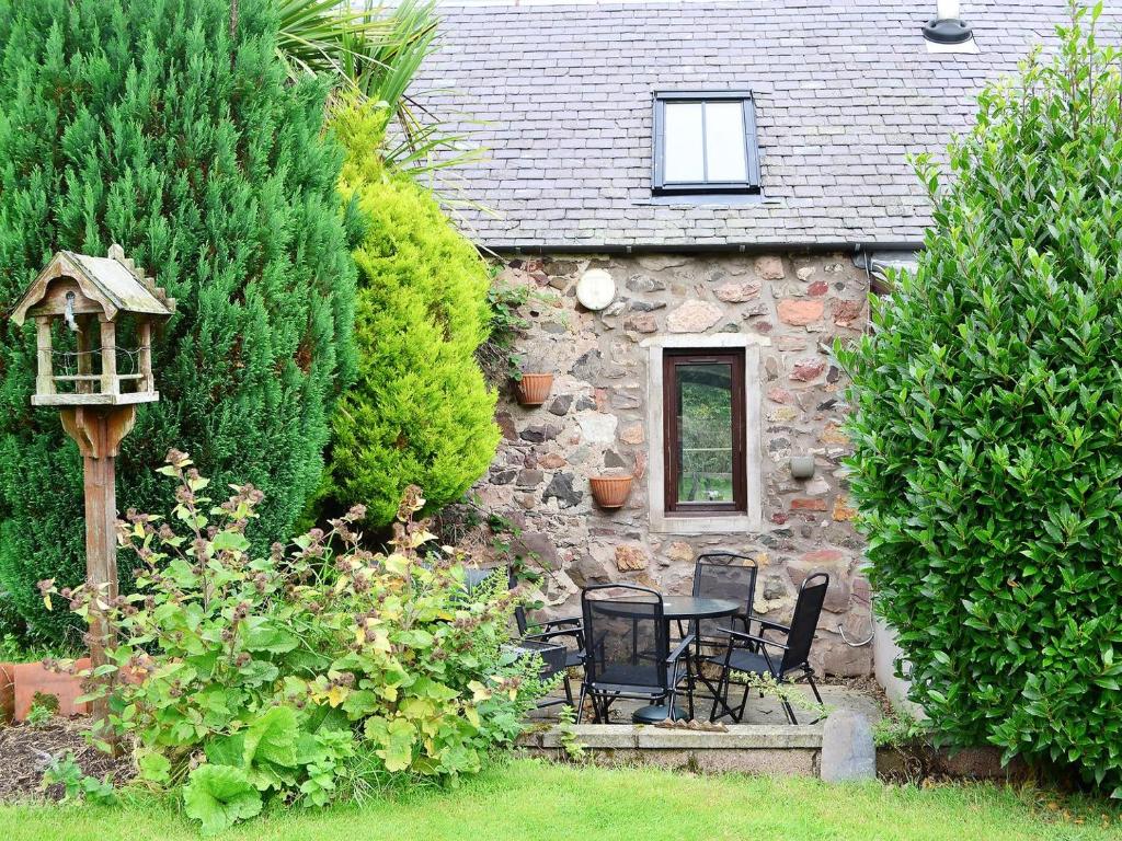a stone cottage with a table and chairs in a garden at Garden Cottage in Coldingham