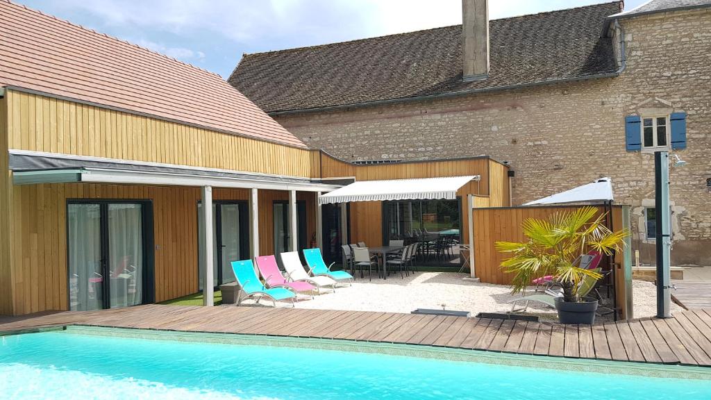 un patio con sillas y una piscina al lado de un edificio en Au Petit Pressoir B&B, en Givry