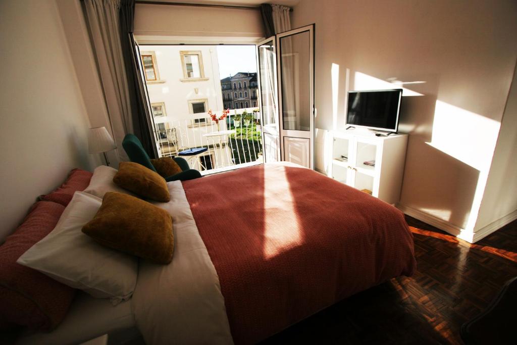 una camera con letto e un balcone con TV di Oleiros Rooms City Center a Coimbra