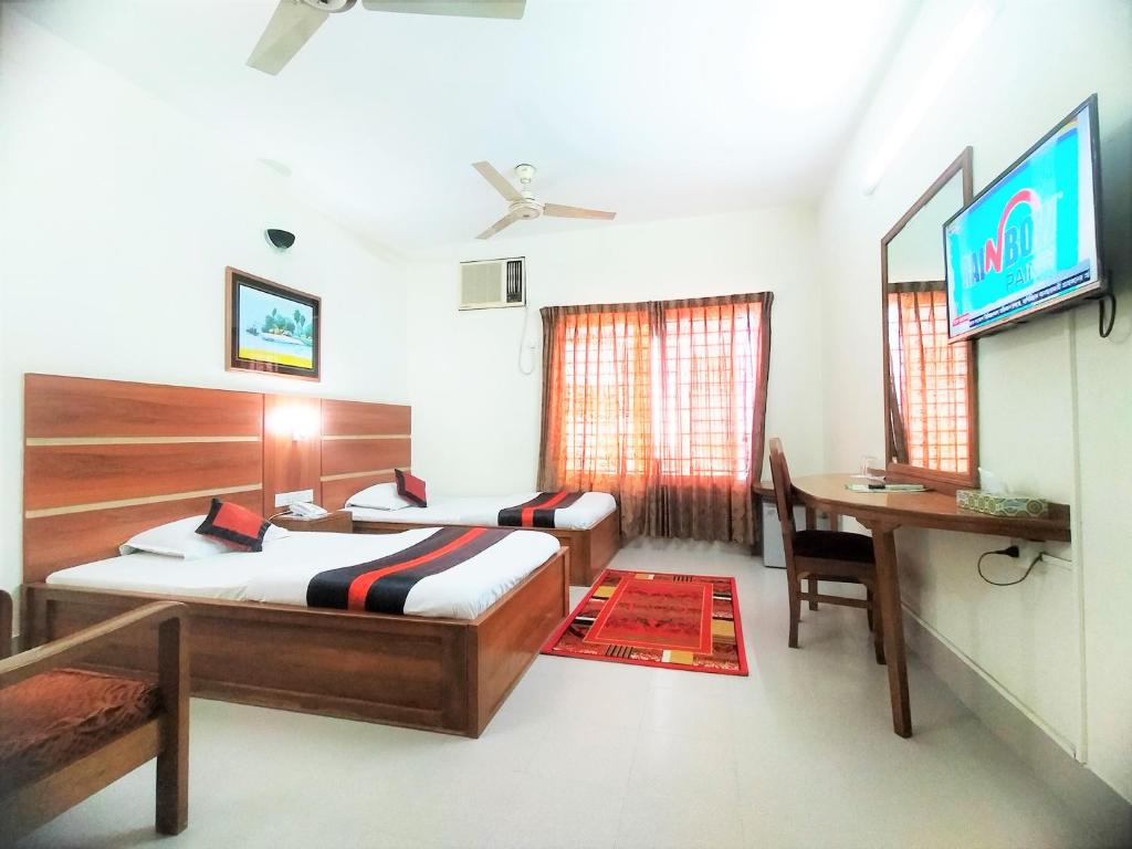 a bedroom with two beds and a desk and a television at Hotel Supreme in Sylhet