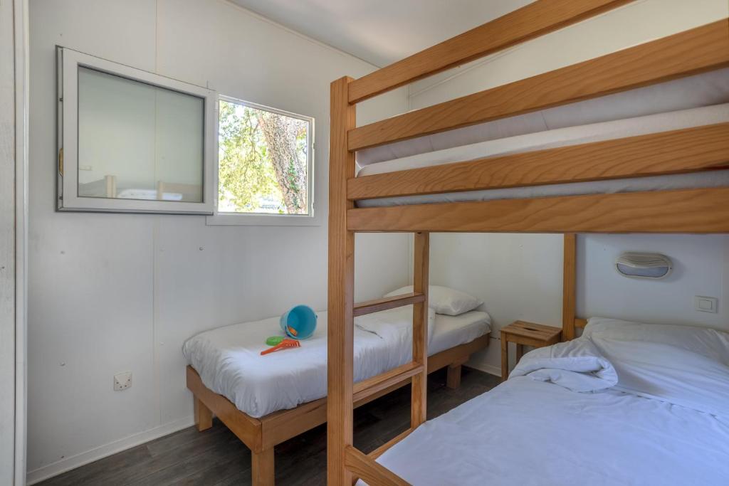 a bedroom with two bunk beds and a window at Village Vacances La Forêt des Landes in Labenne