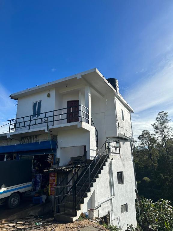 a white building with a staircase in front of it at Sushi guest - mini in Nuwara Eliya