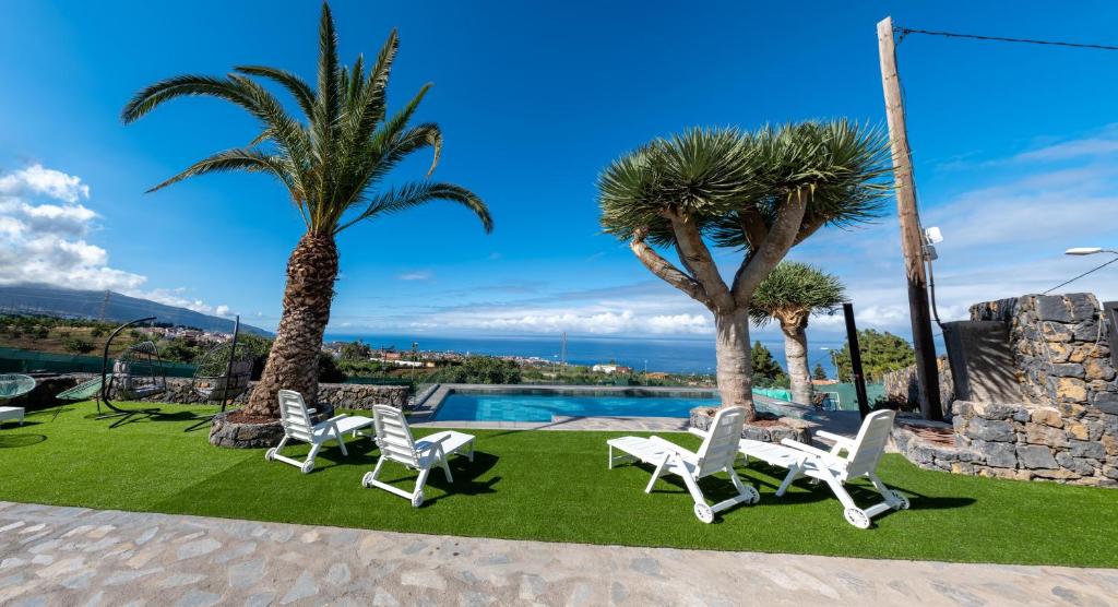 een groep stoelen en palmbomen naast een zwembad bij Estancia Julia in La Orotava