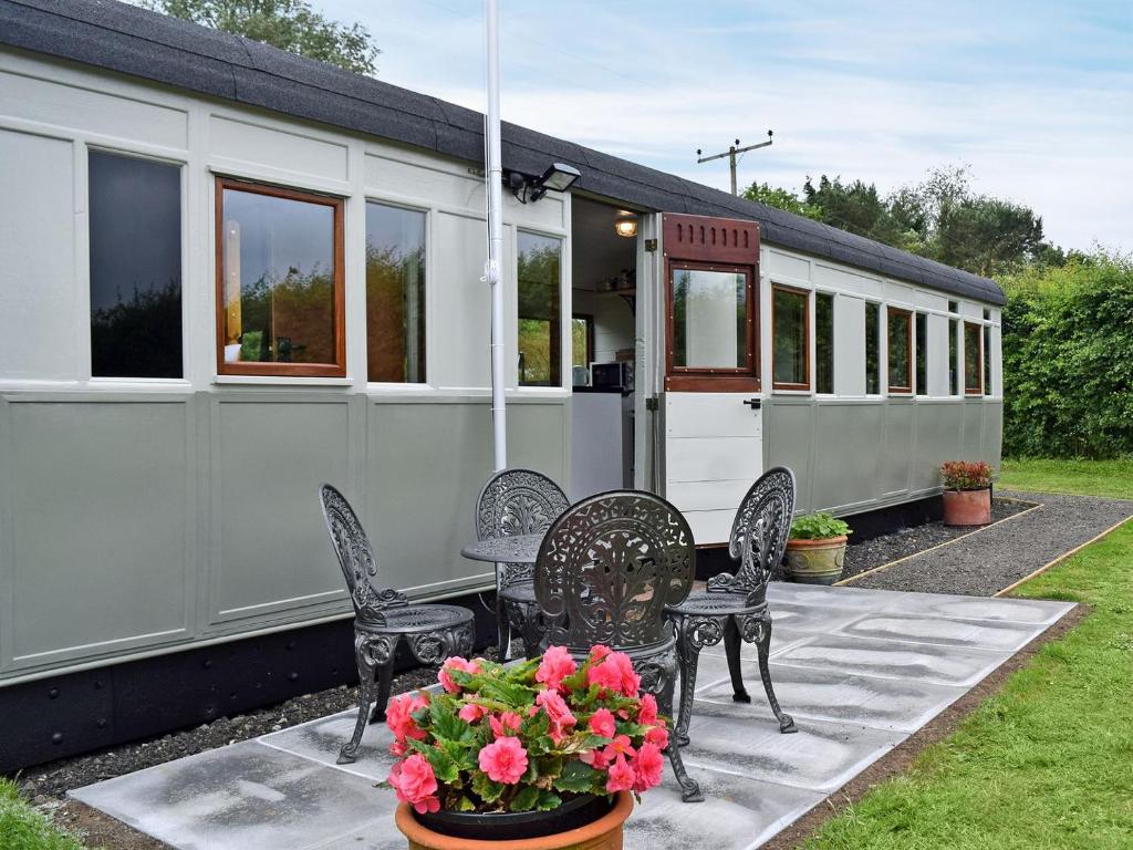 a caravan with chairs and a table and flowers at Italian Carriage-ukc3492 in Wetheringsett