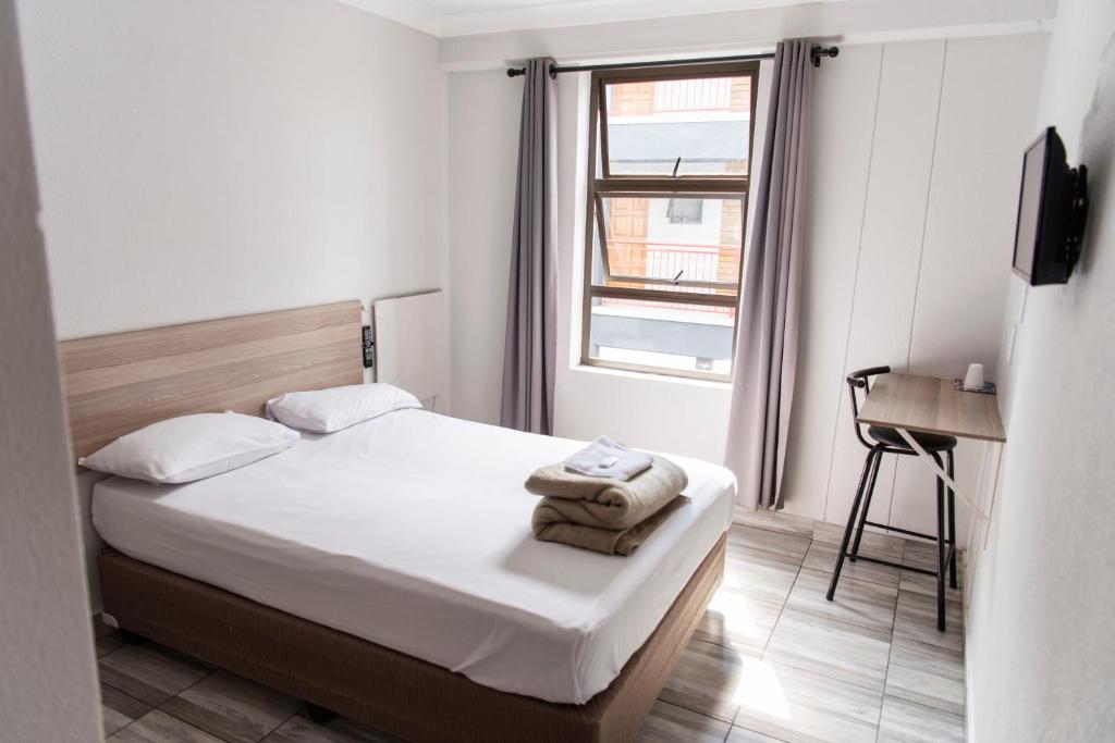 um pequeno quarto com uma cama e uma janela em Ecomotel Louis Botha em Joanesburgo