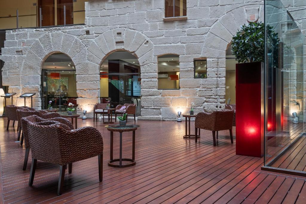 un vestíbulo con sillas, mesas y una pared de piedra en F&G Logroño en Logroño