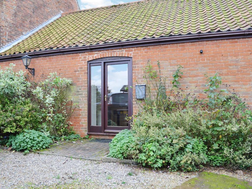 a brick house with a sliding glass door at Barnex in Clippesby