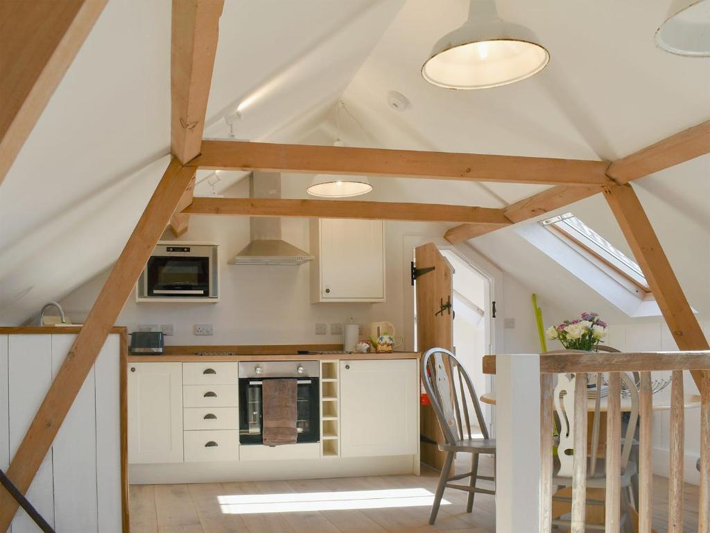 a kitchen with white cabinets and a vaulted ceiling at The Hay Barn - Ukc4135 in Arlingham
