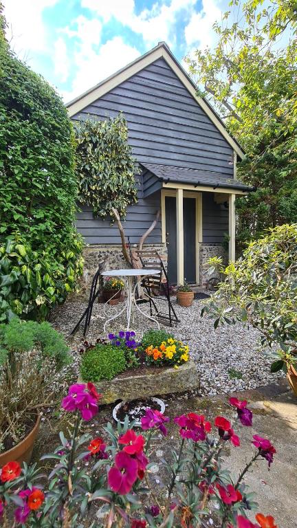 una casa con una mesa y flores delante de ella en The Cabin, Litlington - Dogs Welcome! en Litlington